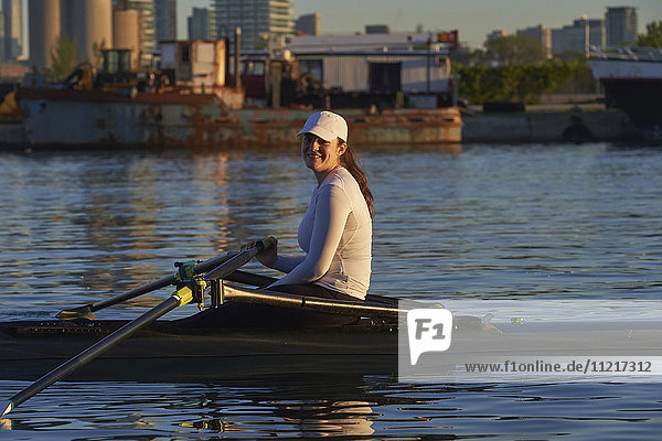 Young woman in a single scull  Hanlan Boat Club in the harbour; Toronto  Ontario  Canada
