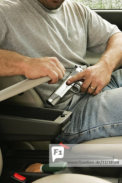 Man Putting Handgun In Car Compartment