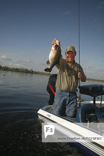 Bass Fisherman With Fish On Boat