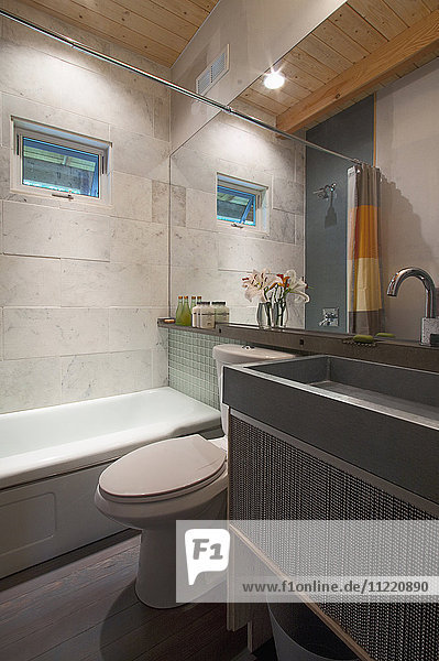 Modernes Badezimmer mit Badewanne und Waschbecken am Spiegel