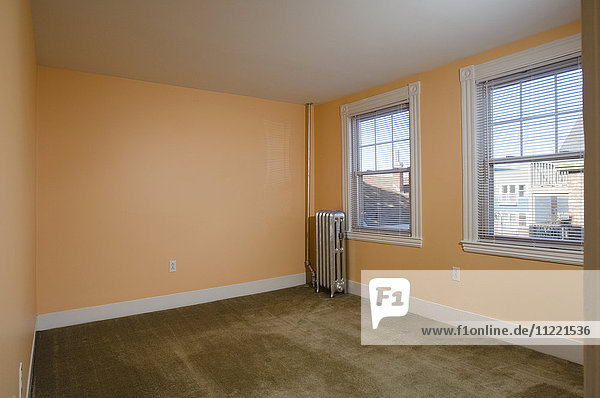 Zimmer in einer leeren Wohnung mit Teppichboden und einer Heizung