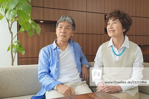 Fashionable Japanese senior couple on sofa