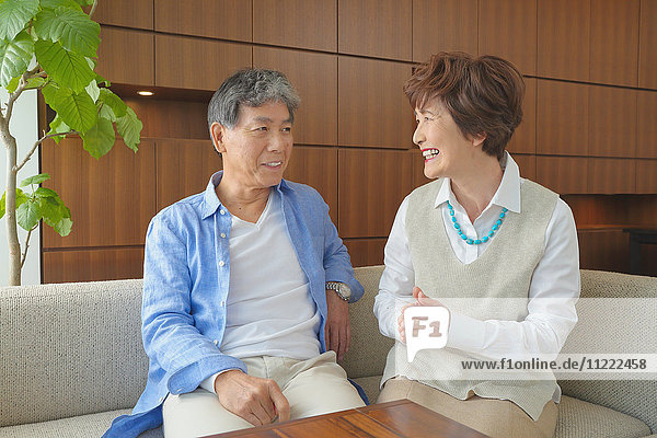 Fashionable Japanese senior couple on sofa