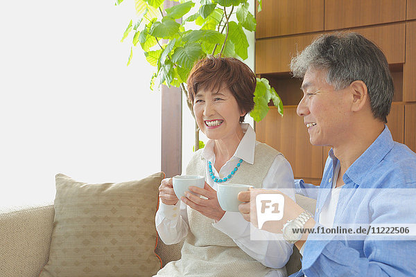 Fashionable Japanese senior couple enjoying a cup of coffee