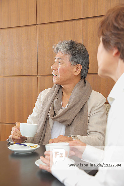 Modisches japanisches Seniorenpaar bei einer Tasse Kaffee