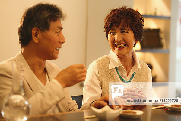 Modisches japanisches Seniorenpaar  das sich im Restaurant amüsiert