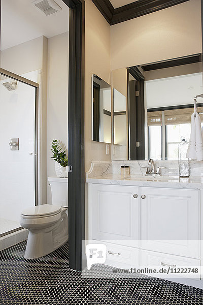 Weiße Schränke und Waschbecken mit Kommode im Badezimmer zu Hause