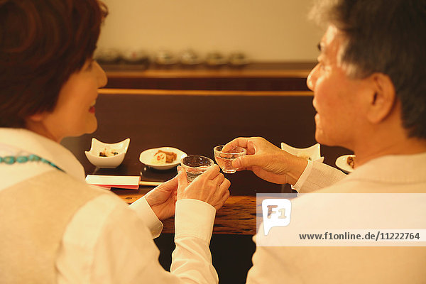 Modisches japanisches Seniorenpaar  das sich im Restaurant amüsiert