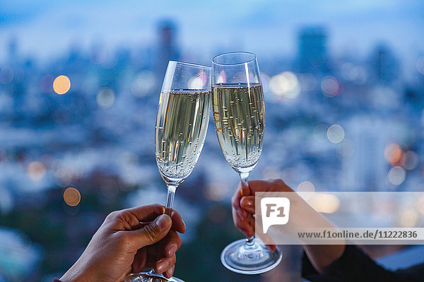 Anstoßen mit Champagner vor der Stadtkulisse Tokios