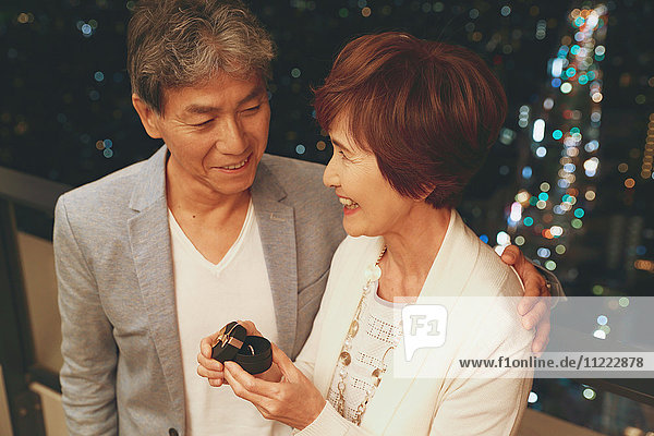 Modisches japanisches Seniorenpaar beim Feiern mit Tokio-Stadtbild im Hintergrund
