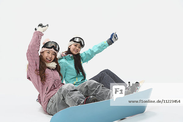 Junge japanische Frauen in Snowboardkleidung auf weißem Hintergrund