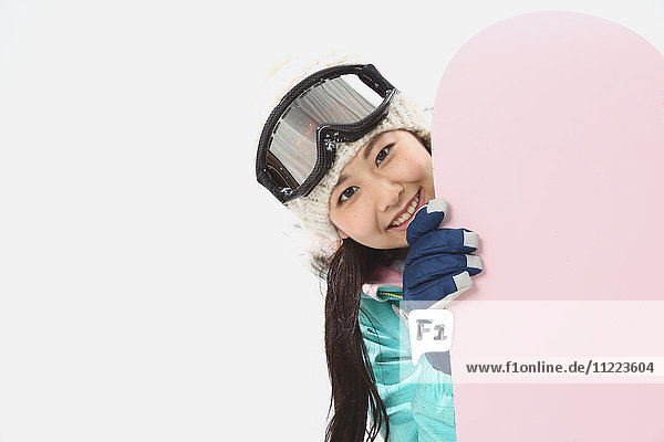 Young Japanese woman wearing snowboard wear on white background