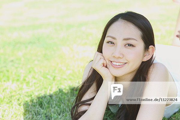 Portrait of young Japanese woman laying on green grass