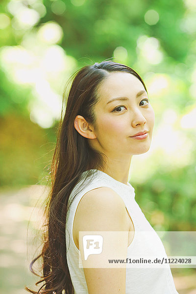 Young Japanese woman surrounded by green in a city park