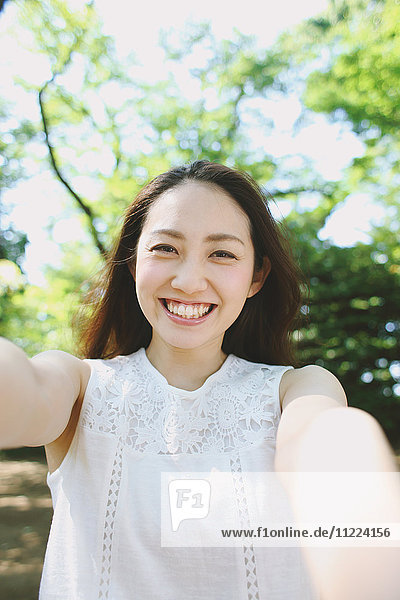 Young Japanese woman surrounded by green in a city park