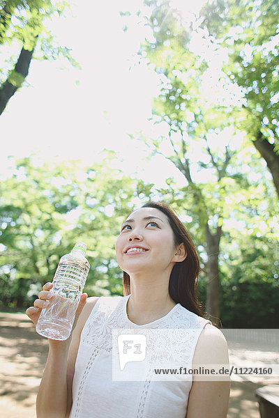 Young Japanese woman drinking water in a city park