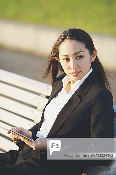 Young Japanese businesswoman with tablet by a river downtown Tokyo