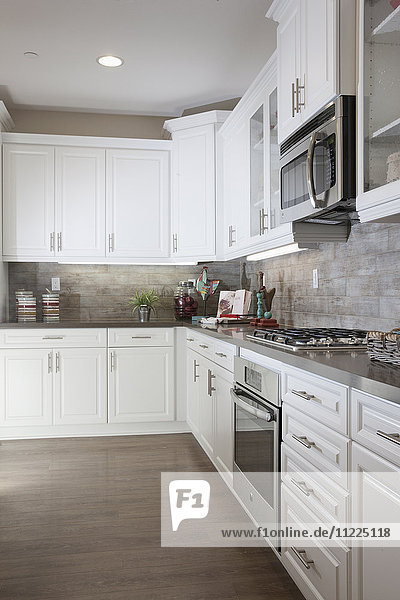Küche mit weißen Schränken und Holzboden zu Hause