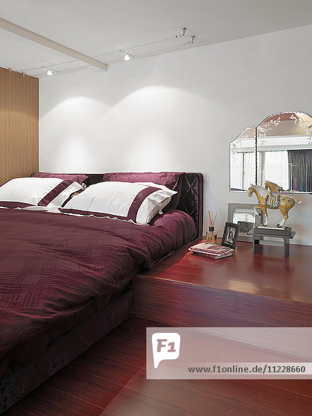 Rotes Bett und Hartholzboden im modernen Schlafzimmer