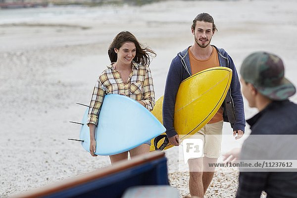Junges Paar am Strand mit Surfbrettern