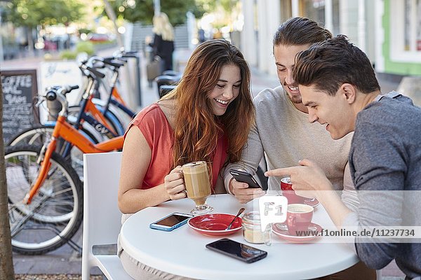 Drei junge Freunde mit Smartphone