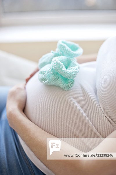 Schwangere Frau mit Babyschuhen auf dem Bauch