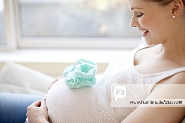 Schwangere Frau mit Babyschuhen auf dem Bauch