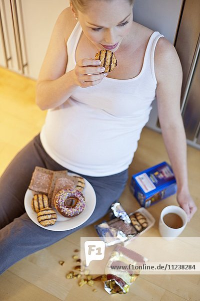 Schwangere Frau isst Kekse
