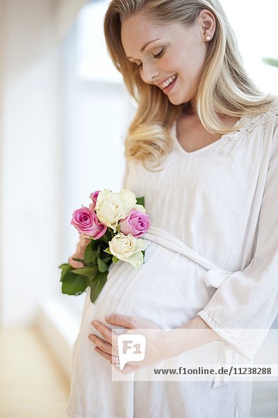 Schwangere Frau hält Blumenstrauß