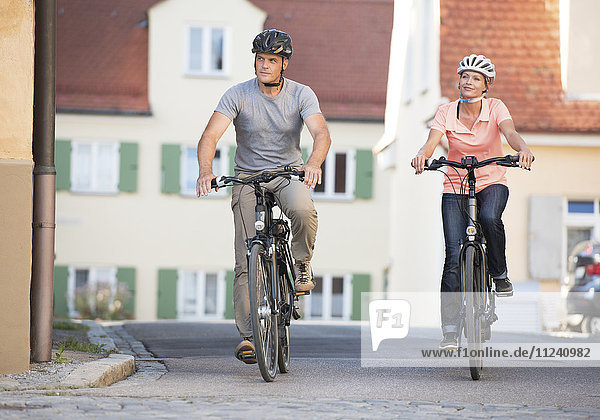Paar fährt mit E-Bikes durch eine Stadt