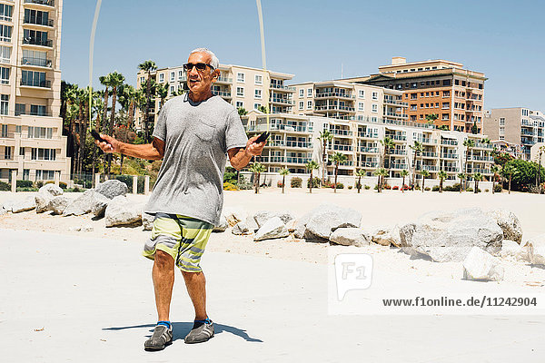 Senior man  skipping on beach  Long Beach  California  USA