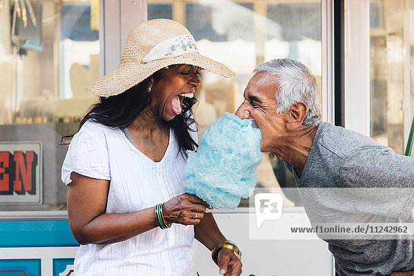 Senior couple eating cotton candy  laughing  Long Beach  California  USA