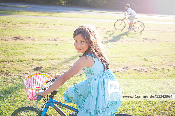 Junges Mädchen und Junge fahren Fahrrad in der Sommersonne