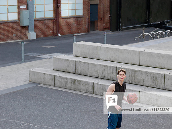 Junger Mann spielt Basketball im Freien