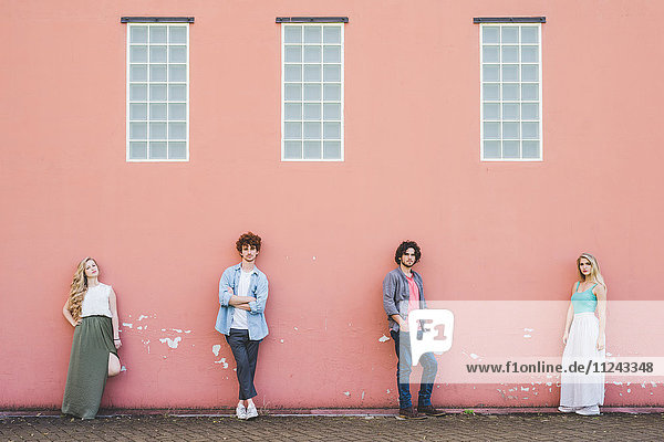 Friends standing against pink wall background