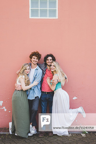 Couples hugging against pink wall background