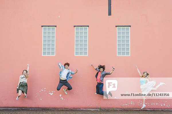 Friends jumping against pink wall background