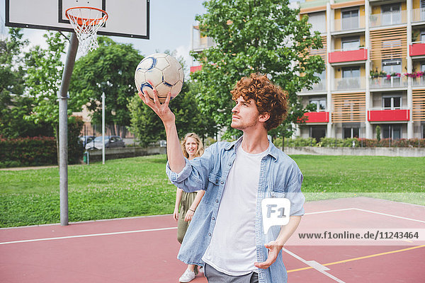 Man balancing basketball  girlfriend in background