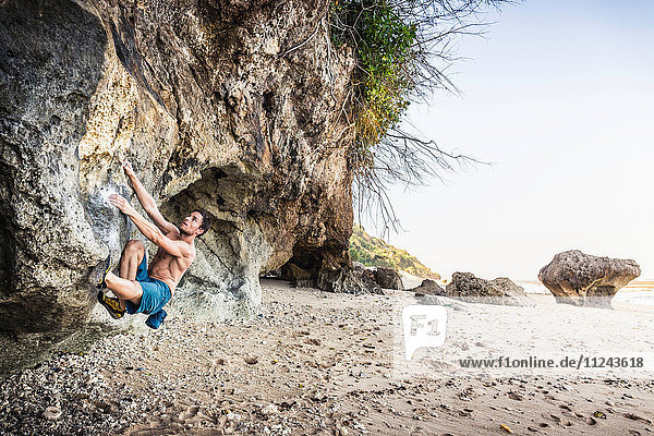 Male free climber climbing rock face on Pandawa Beach Bali Indonesia