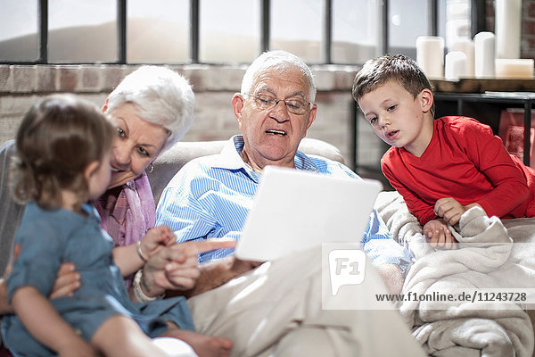 Großeltern  die mit Enkelkindern spielen  benutzen zu Hause ein digitales Tablett.