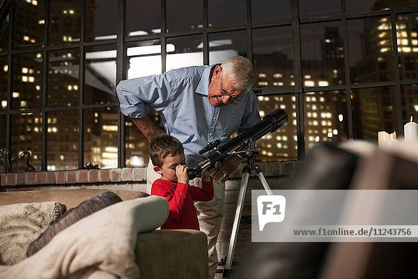 Großvater lehrt Enkel  das Teleskop zu Hause zu benutzen.
