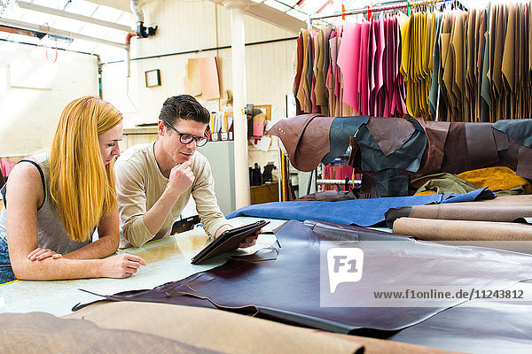 Männliche und weibliche Kollegen arbeiten zusammen und befassen sich mit digitalen Tabletts bei Lederjackenherstellern