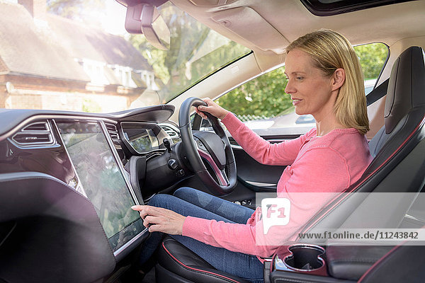 Woman using satellite navigation system in electric car