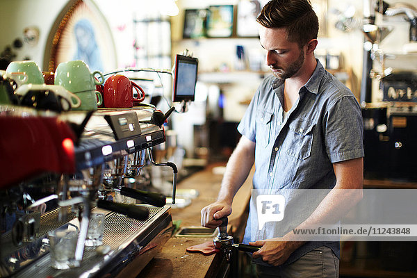 Young man preparing coffee at cafe kitchen counter