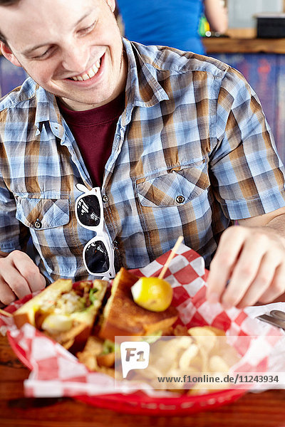 Junger Mann isst Fastfood und lächelt