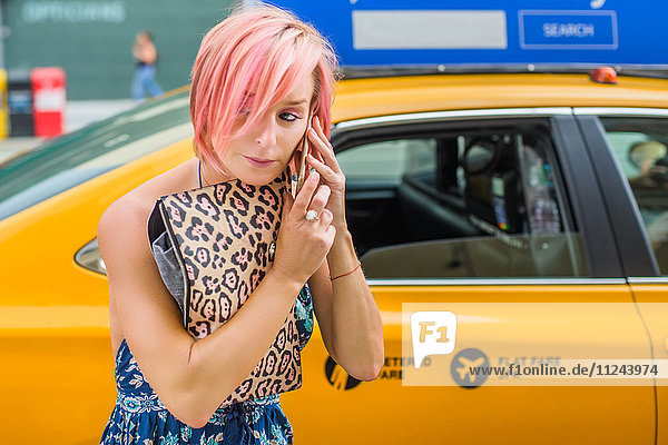 Reife Frau  die neben einem Taxi steht und ein Smartphone benutzt