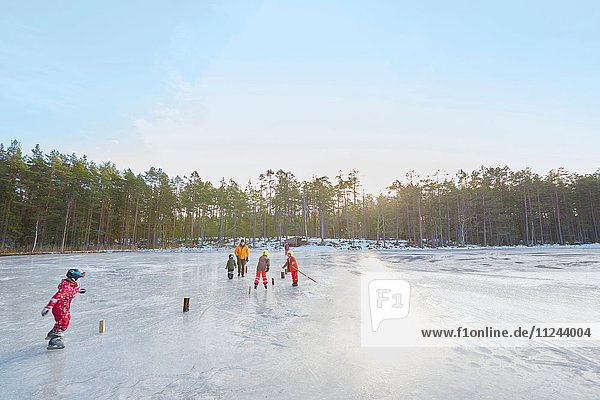 Älteres Ehepaar und Enkelkinder üben Eislaufslalom auf dem zugefrorenen See  Gavle  Schweden