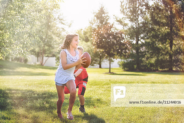 Mädchen und Junge spielen American Football