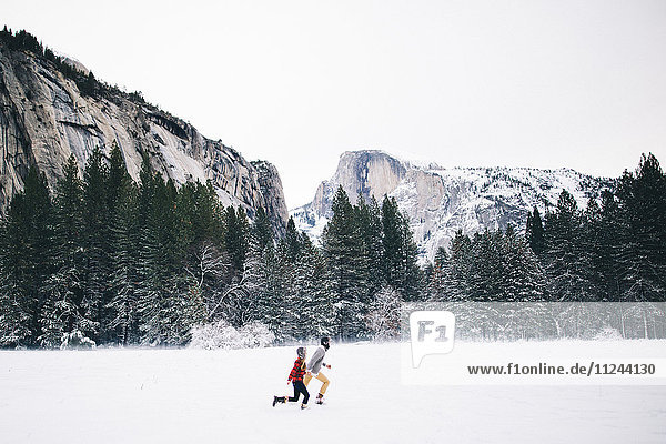 Seitenansicht eines Paares beim Laufen in schneebedeckter Landschaft