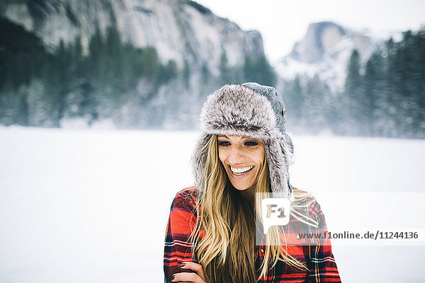 Rückansicht einer Frau mit Uschanka-Hut auf schneebedeckter Landschaft